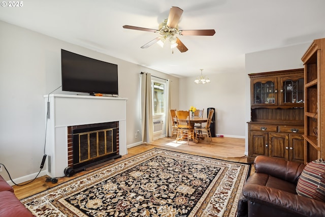 722 E 14th St, The Dalles, OR 97058 - living area with a ceiling fan, light wood-style flooring, baseboards, a brick fireplace, and a chandelier