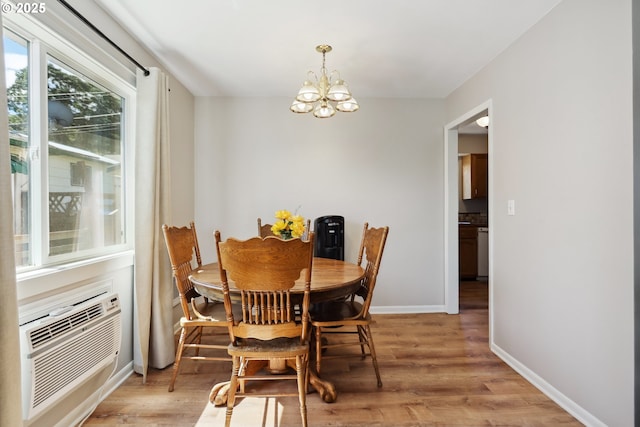 722 E 14th St, The Dalles, OR 97058 - dining room featuring light wood finished floors, a chandelier, a wall unit AC, and baseboards