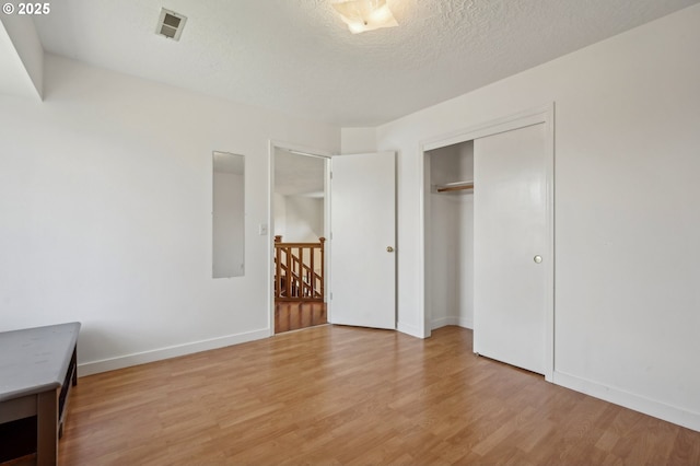 950 NW 161st Ter, Beaverton, OR 97006 - unfurnished bedroom with light wood finished floors, a textured ceiling, baseboards, visible vents, and a closet