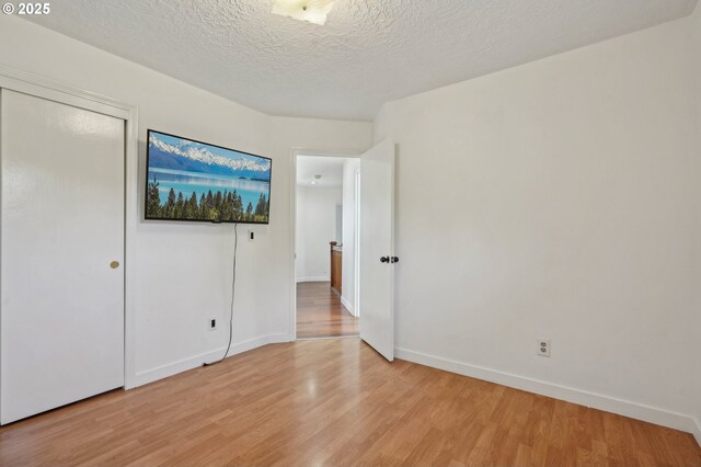 950 NW 161st Ter, Beaverton, OR 97006 - unfurnished bedroom featuring light wood-type flooring, baseboards, a textured ceiling, and a closet