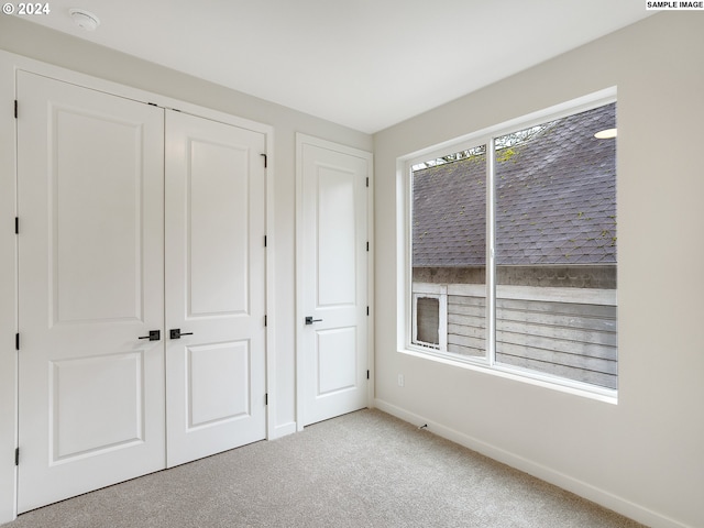 unfurnished bedroom with light carpet and a closet