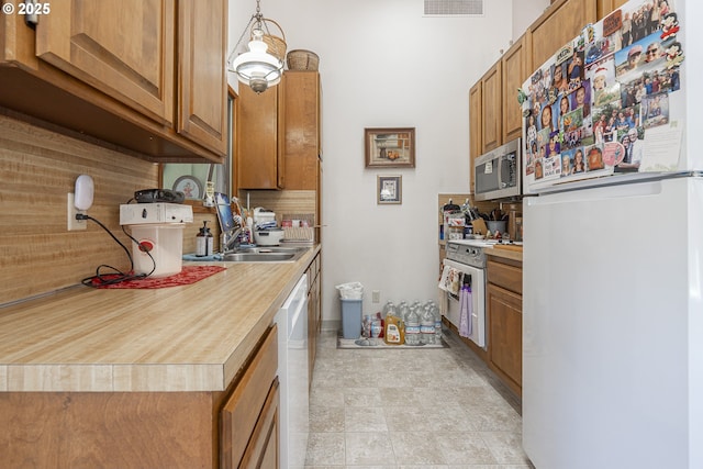 3419 S Ballard Ln, Lincoln City, OR 97367 - kitchen with white appliances, decorative backsplash, light countertops, and brown cabinetry