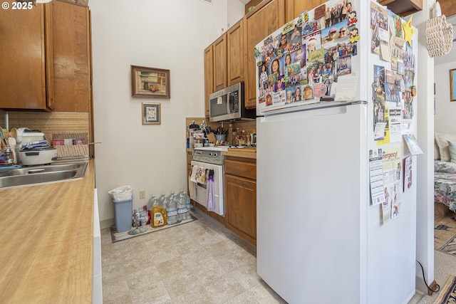 3419 S Ballard Ln, Lincoln City, OR 97367 - kitchen featuring freestanding refrigerator, stainless steel microwave, a sink, stove, and decorative backsplash