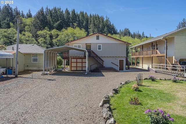 3419 S Ballard Ln, Lincoln City, OR 97367 - rear view of house with stairway, gravel driveway, an outdoor structure, a detached carport, and a yard
