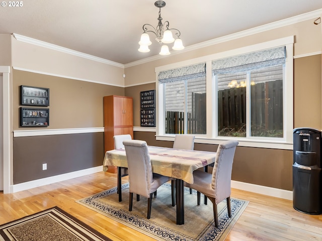 dining area with light wood-type flooring, crown molding, and an inviting chandelier