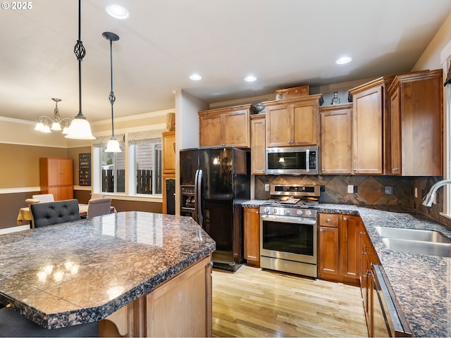 kitchen with a center island, sink, hanging light fixtures, tasteful backsplash, and stainless steel appliances