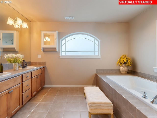 bathroom with tile patterned flooring, vanity, and tiled tub