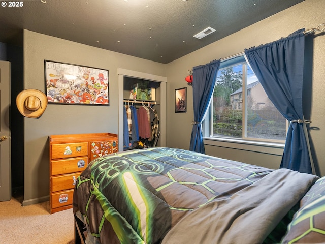 bedroom with a textured ceiling, carpet floors, and a closet