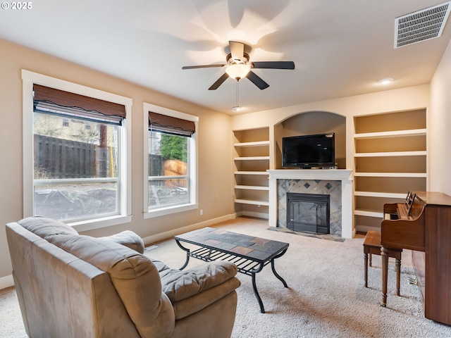 carpeted living room with built in shelves, ceiling fan, and a fireplace