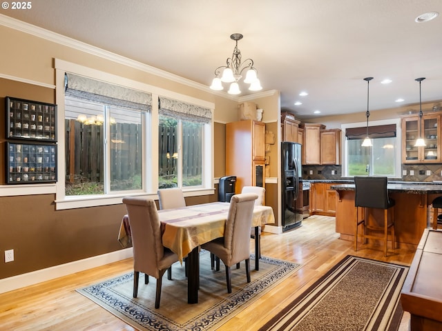 dining space featuring light hardwood / wood-style floors, ornamental molding, and a chandelier