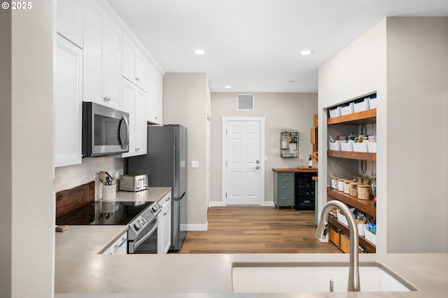 9619 NW Silver Ridge Loop, Portland, OR 97229 - kitchen with appliances with stainless steel finishes, a sink, light wood finished floors, tasteful backsplash, and white cabinetry