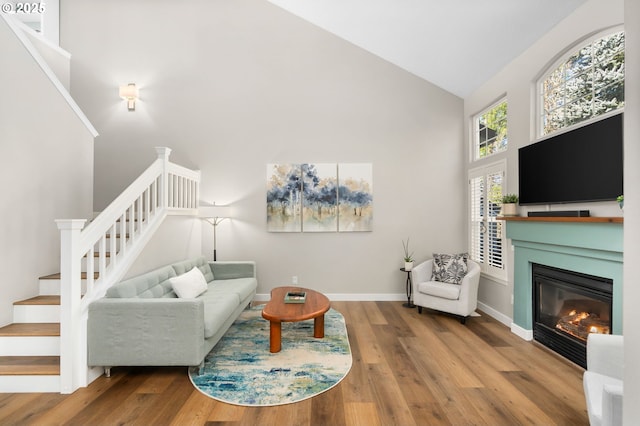 9619 NW Silver Ridge Loop, Portland, OR 97229 - living room featuring high vaulted ceiling, stairs, wood finished floors, a glass covered fireplace, and baseboards