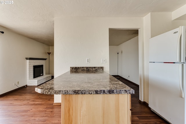 786788 W Quinalt St, Springfield, OR 97477 - kitchen with freestanding refrigerator, wood finished floors, a textured ceiling, a peninsula, and a fireplace