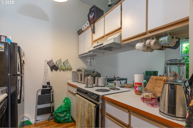 1910 SW 18th Ave Unit 23, Portland, OR 97201 - kitchen with range with electric cooktop, freestanding refrigerator, under cabinet range hood, light countertops, and white cabinets