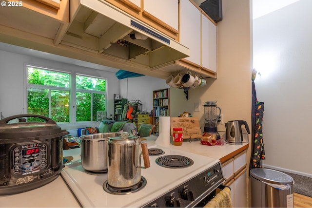 1910 SW 18th Ave Unit 23, Portland, OR 97201 - kitchen with white electric range oven, light countertops, white cabinetry, and extractor fan