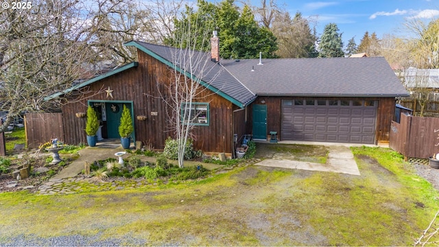 view of front facade featuring a garage, a shingled roof, fence, driveway, and a chimney