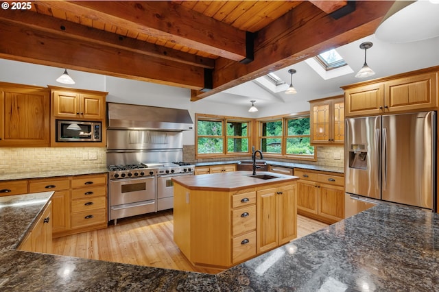 kitchen featuring stainless steel appliances, wall chimney exhaust hood, a sink, a skylight, and light wood-type flooring