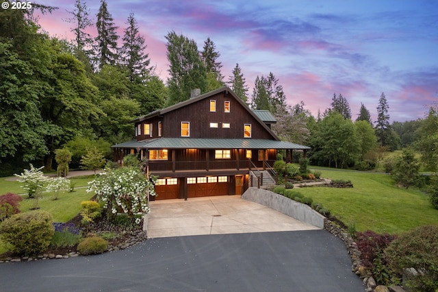 view of front facade featuring a porch, concrete driveway, an attached garage, and a yard