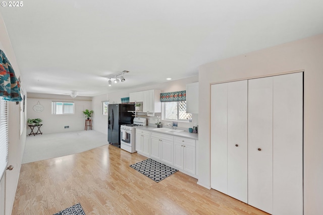 6 Creek Ln, Lakeside, OR 97449 - kitchen with white gas stove, a sink, light countertops, light wood finished floors, and white cabinetry