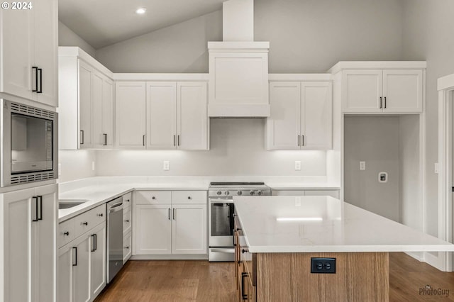 kitchen featuring lofted ceiling, a kitchen island, appliances with stainless steel finishes, light hardwood / wood-style floors, and white cabinetry