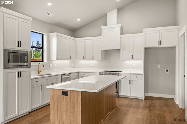 kitchen with white cabinetry, a center island, stainless steel appliances, and sink