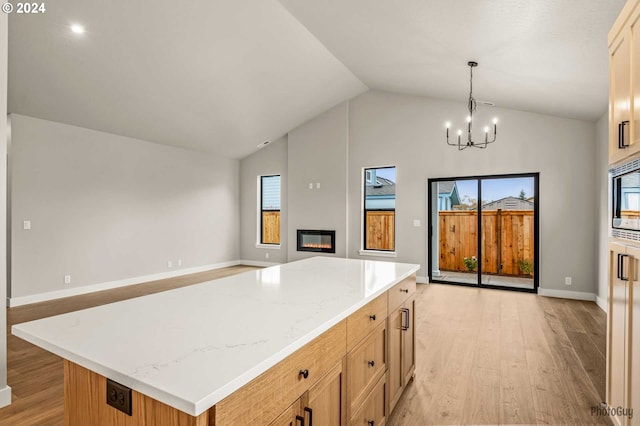 kitchen featuring pendant lighting, vaulted ceiling, light wood-type flooring, a wealth of natural light, and a kitchen island