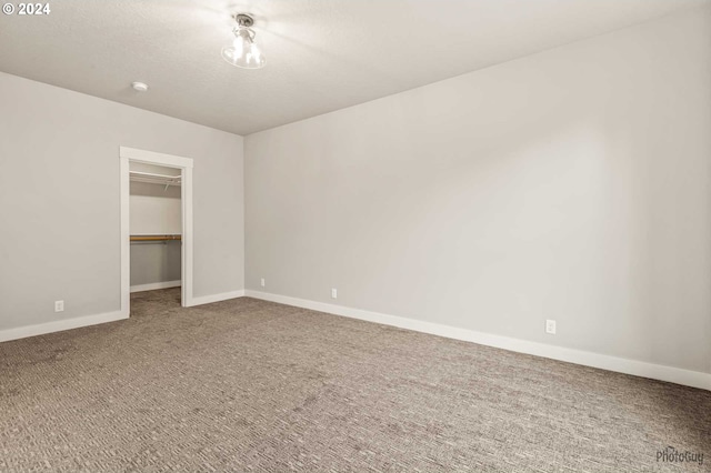 unfurnished bedroom featuring a walk in closet, a closet, and carpet