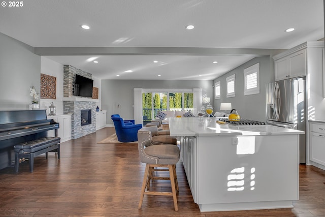 kitchen featuring white cabinets, a center island, dark hardwood / wood-style flooring, a fireplace, and a breakfast bar area