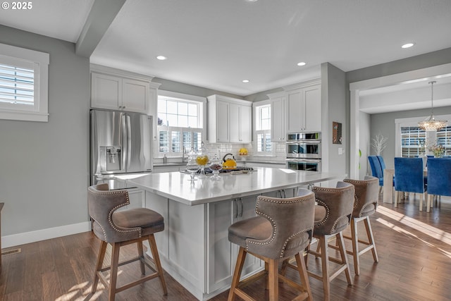 kitchen with a kitchen island, stainless steel appliances, tasteful backsplash, hanging light fixtures, and a breakfast bar area