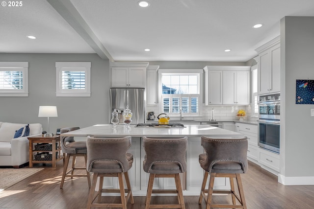 kitchen featuring a center island, a kitchen bar, white cabinets, backsplash, and stainless steel appliances