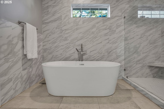 bathroom featuring shower with separate bathtub, tile walls, and tile patterned flooring