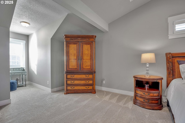 bedroom with vaulted ceiling, light colored carpet, a textured ceiling, and multiple windows