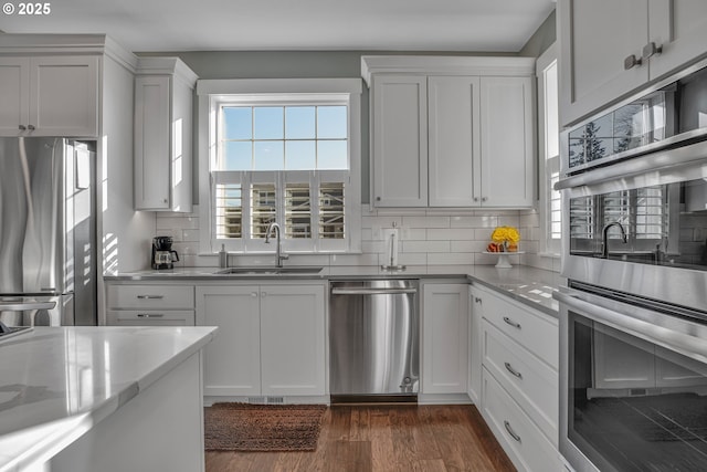 kitchen with sink, stainless steel appliances, white cabinetry, and dark wood-type flooring