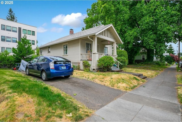 4435 SE Belmont St, Portland, OR 97215 - view of front facade with covered porch, a chimney, and a front yard