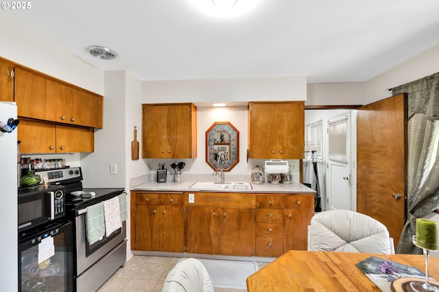 17222 SW Blanton St, Beaverton, OR 97078 - kitchen with stainless steel electric range oven, black microwave, light countertops, and brown cabinetry