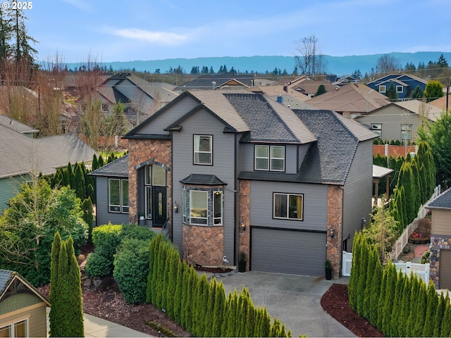 view of front facade with a residential view, roof with shingles, driveway, stone siding, and an attached garage