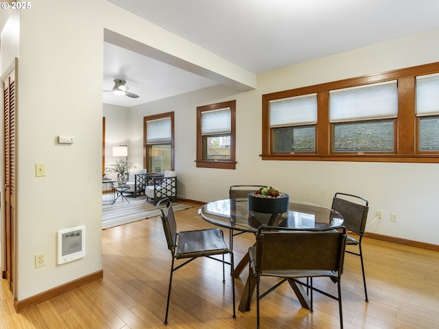 dining space featuring heating unit, light wood-style flooring, and baseboards