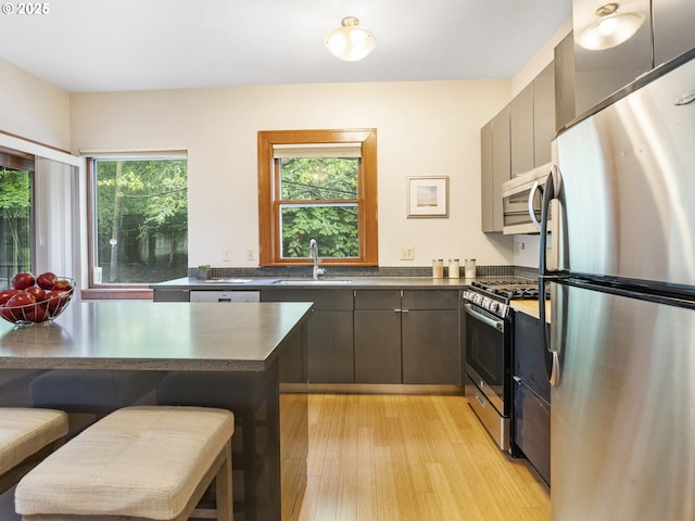 kitchen featuring plenty of natural light, appliances with stainless steel finishes, a kitchen breakfast bar, and a sink