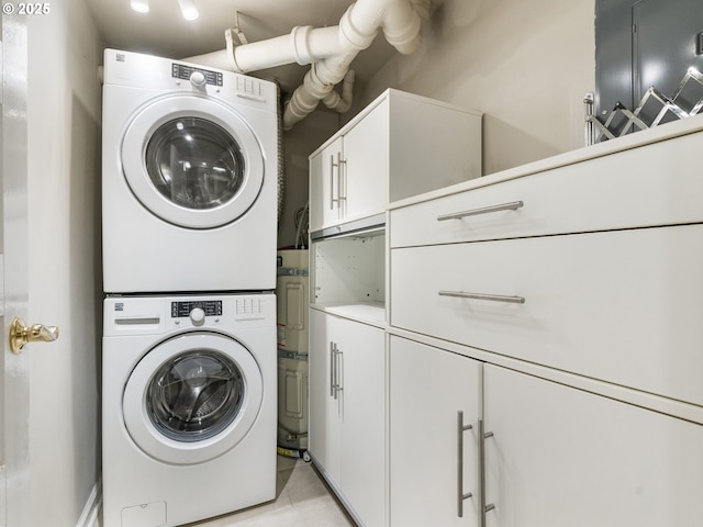 washroom with stacked washer / drying machine and cabinet space