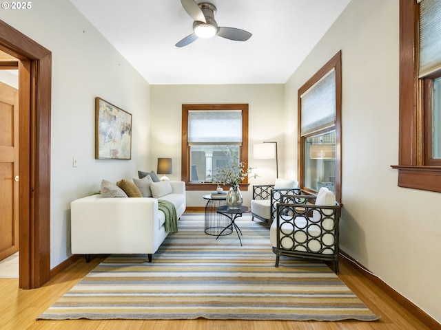 living area with ceiling fan, baseboards, and wood finished floors