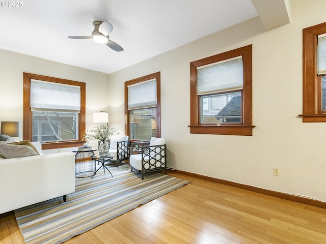 living room with light wood-style flooring, baseboards, and ceiling fan