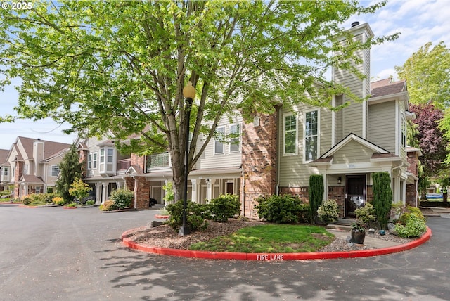 townhome / multi-family property featuring a chimney and brick siding