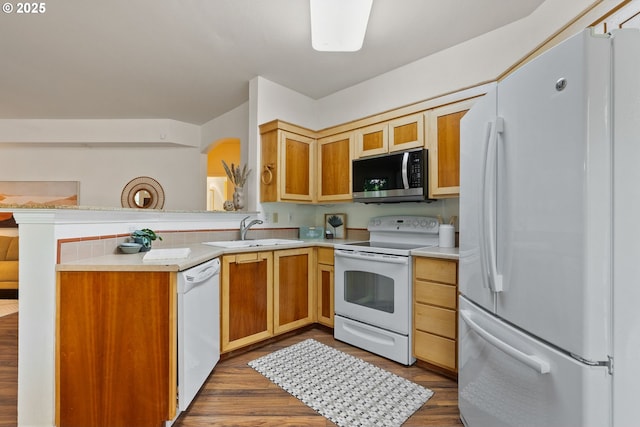 kitchen featuring white appliances, a sink, light countertops, and dark wood finished floors