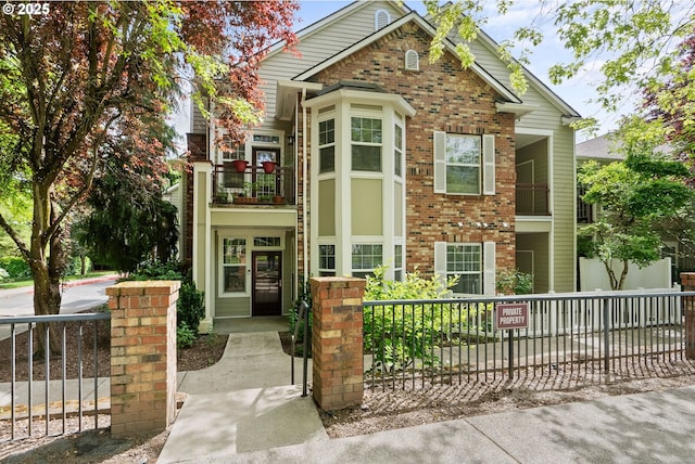 view of front of house with brick siding, a fenced front yard, and a balcony