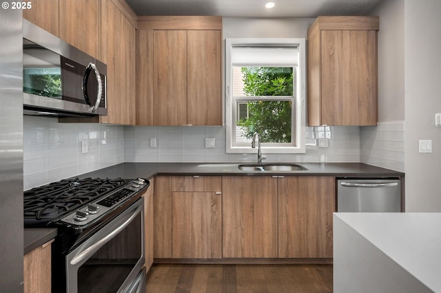 5942 NE 42nd Ave, Portland, OR 97218 - kitchen with appliances with stainless steel finishes, dark countertops, modern cabinets, decorative backsplash, and brown cabinetry