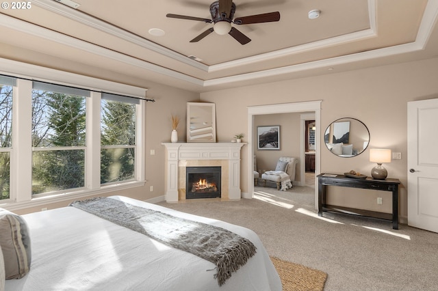 bedroom with a raised ceiling, light carpet, and ceiling fan