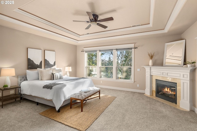 bedroom with a tiled fireplace, carpet, ceiling fan, and a tray ceiling