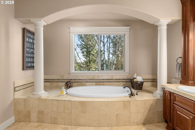 bathroom featuring ornate columns, vanity, and tiled bath