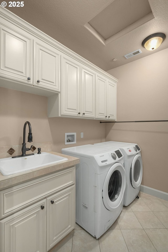 laundry room with sink, cabinets, a textured ceiling, light tile patterned flooring, and separate washer and dryer