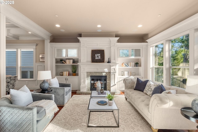 living room with crown molding, a high end fireplace, and light wood-type flooring